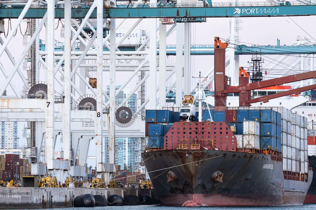 Container ship loaded under port cranes, like versioned packages shipping to product teams