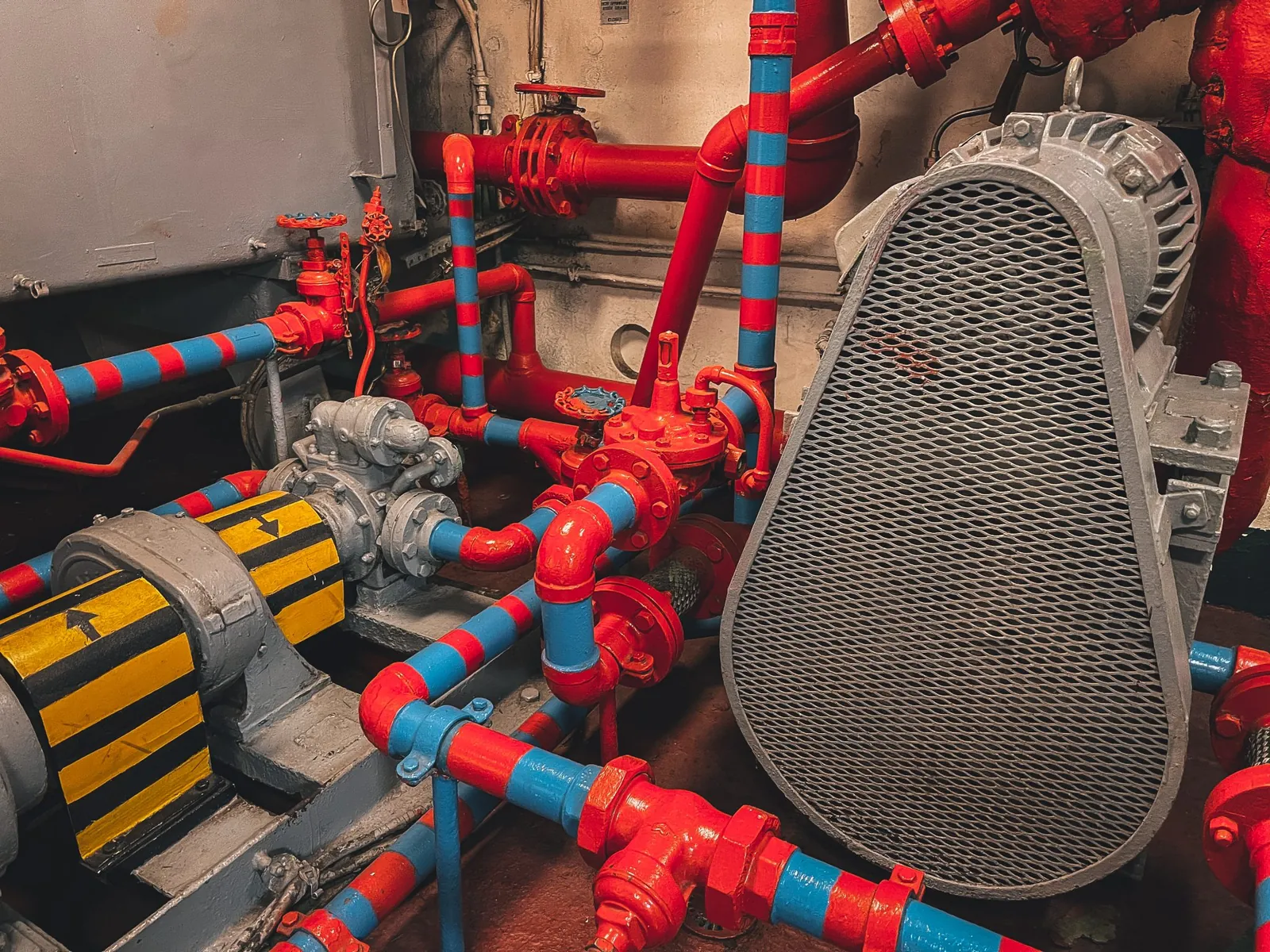 Red pipes and machinery in a ship engine room, like a mature and complex build pipeline