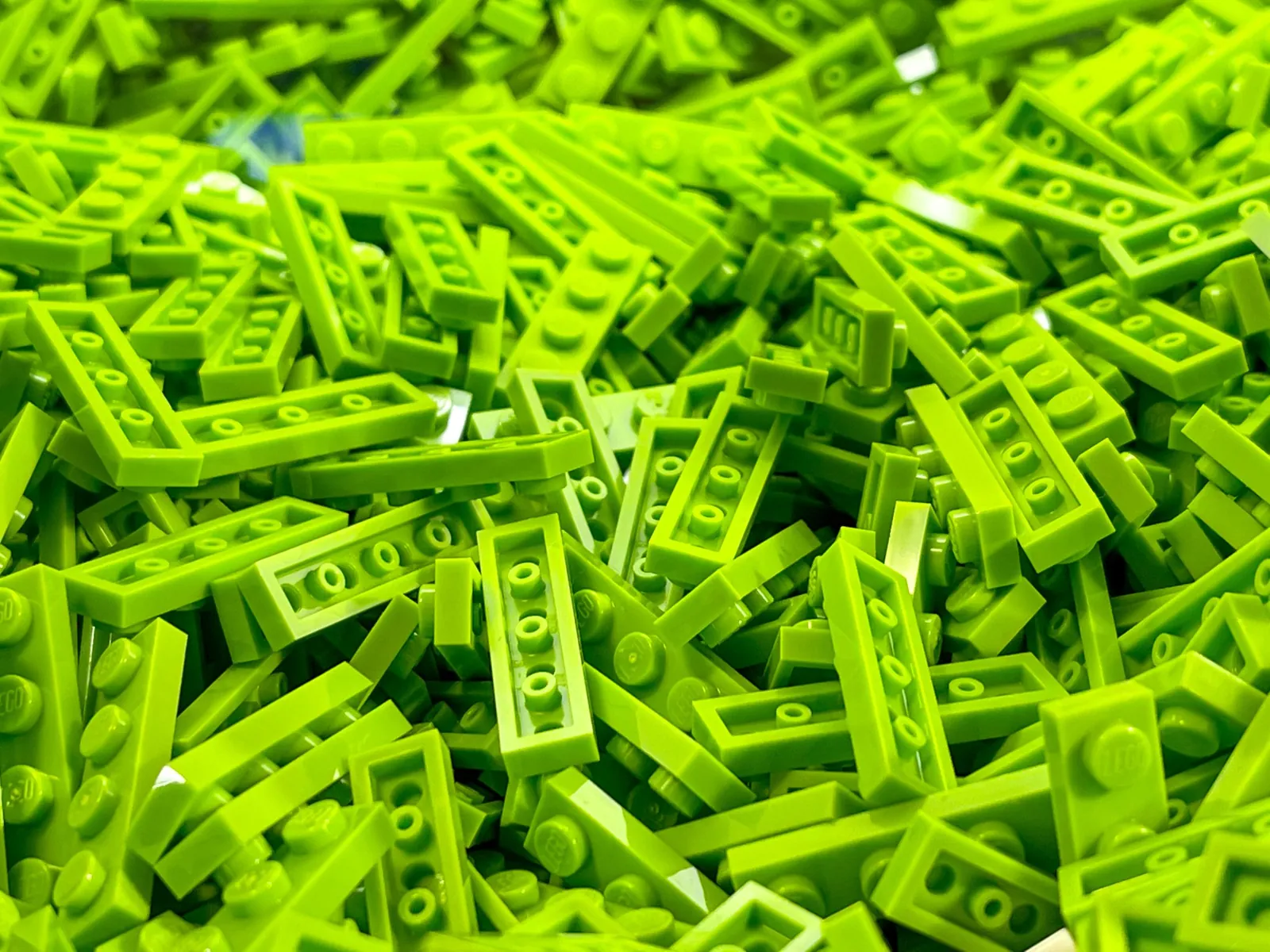 Pile of green toy building bricks, small pieces that compose into larger schemas