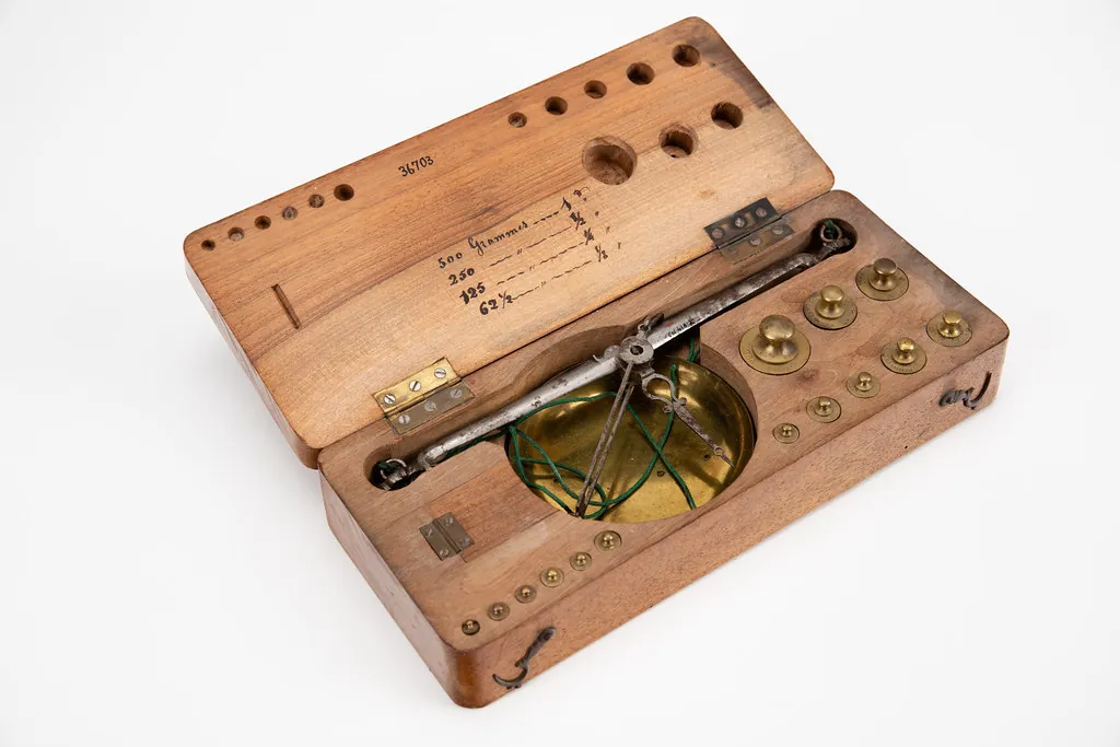 Antique balance scale in a wooden case, weighing a rate against hidden costs