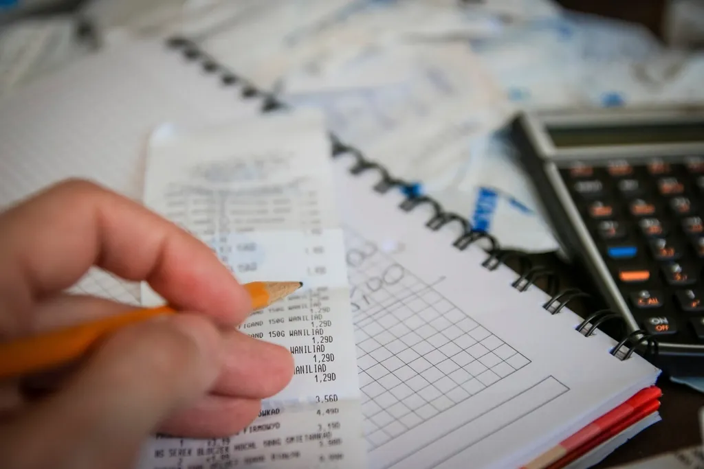 Hand writing figures with a pencil beside a calculator to set a minimum rate