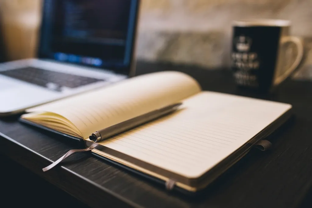 Open notepad beside a laptop showing code, with notes that give useful context