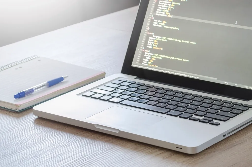 Laptop showing code on a bright desk, building the app layer of a full stack project