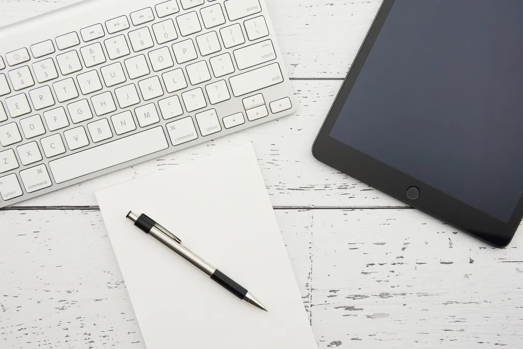 Tablet, keyboard and printed notes on a white desk, prepared for presenting a case study