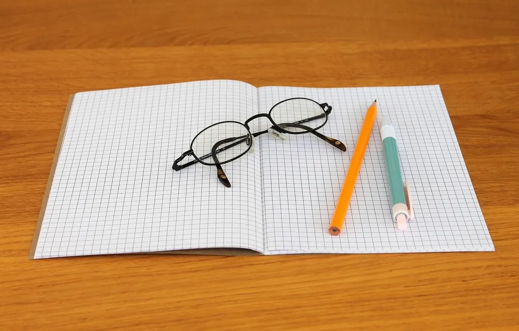 Grid notebook with glasses and pencils, its shared lines keeping every row aligned