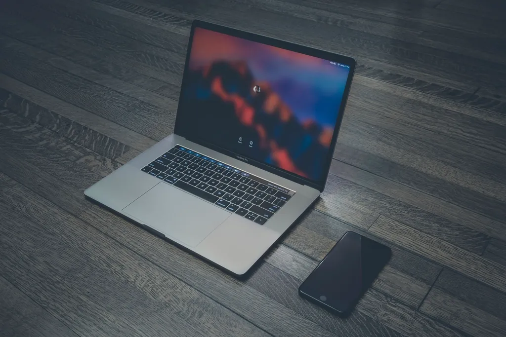Laptop and smartphone on a dark wooden floor, ready for testing a layout on real devices